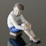 Dreng siddende på bøger, Bing & Grøndahl figur nr. 1742