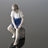 Junge sitzt auf einem Stein und rollt seine Hose auf, Bing & Gröndahl Figur Nr. 1757