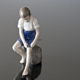 Boy sitting on stone rolling up trousers, Bing & Grondahl figurine No. 1757