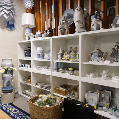 Udstilling hos DPH Trading med porcelænsfigurer, blå-hvide vaser, lysholdere og klassisk brugskunst – et af butikkens mange områder med boligtilbehør og samleobjekter