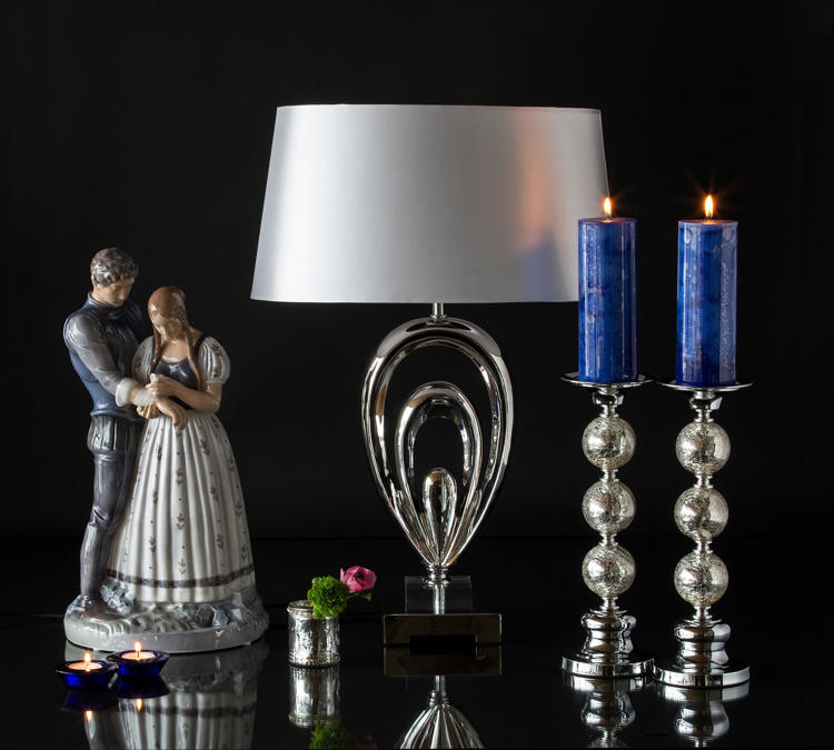 Large Knight and Maiden figurine next to a glass lamp and candlesticks
