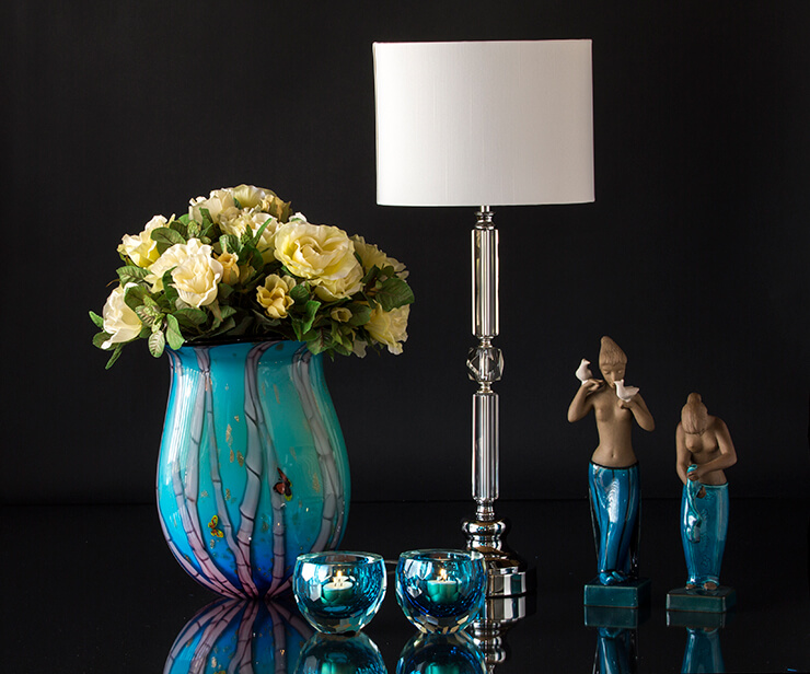 Blå glasvase med fyrfadslysestager og lampe med to figurer