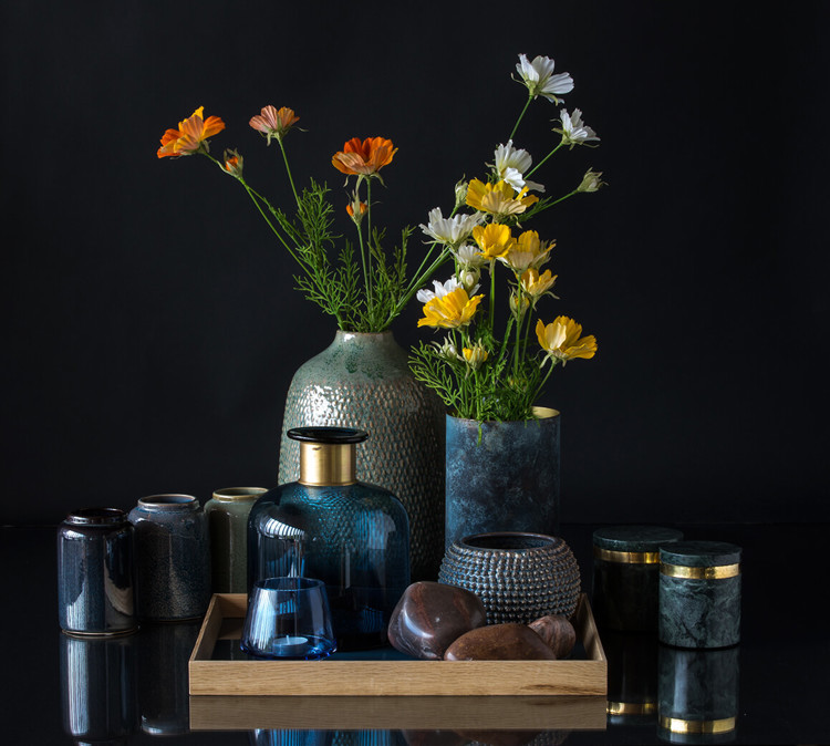 Stor vase med blå flaske og lille urtepotte på bakke med vaser og marmorkrukker omkring