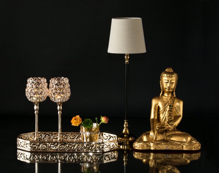 Buddha ved siden af lille lamp og spejlbakke med lysestager