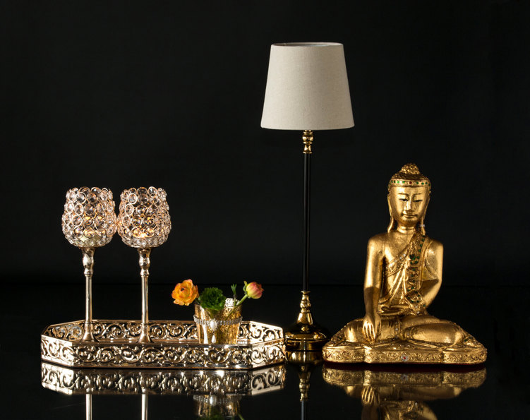 Buddha next to small lamp and mirror tray with candlesticks