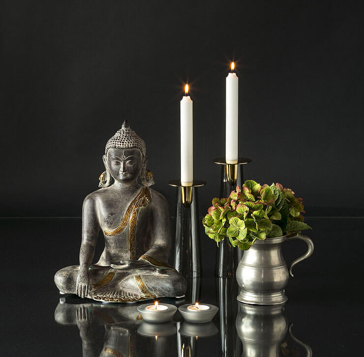Buddha figur med lysestager og vase med blomster