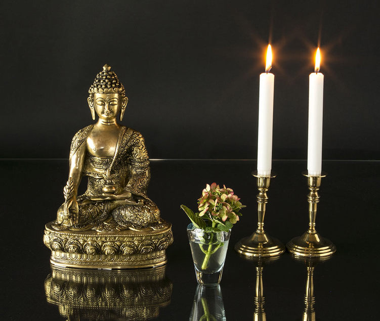 Brass Buddha statue with glass vase with flowers