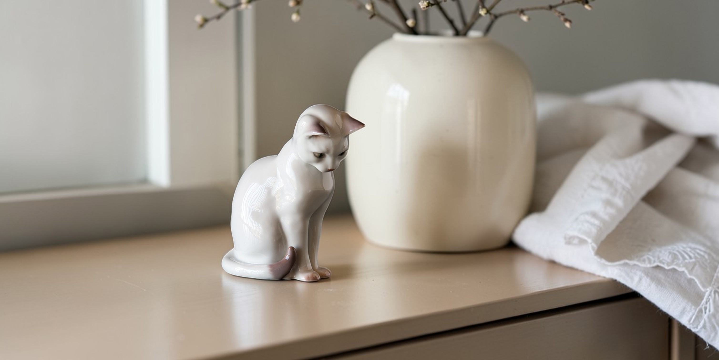 Hvid kattefigur i porcelæn fra Bing & Grøndahl, nr. 2476, klassisk dansk porcelæn kat siddende på bord i boligindretning