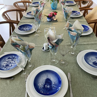 Festligt bord dækket til konfirmation eller fødselsdag med Désirée Mors Dag platter, hvide tallerkener og vinglas. Inspiration til borddækning til fest med grøn dug og blomster.