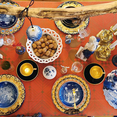 Julebord dækket med Bing & Grøndahl juleplatter, Bjørn Wiinblad juleplatter og Komponiststel kopper, kombineret med andre steldele. Bord i blå, guld og røde nuancer.