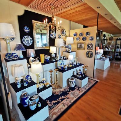 Udstilling med blå-hvidt porcelæn, messingstager og bordlamper i DPH Tradings butik i Odense N. Klassisk og moderne boligindretning i smuk kombination.