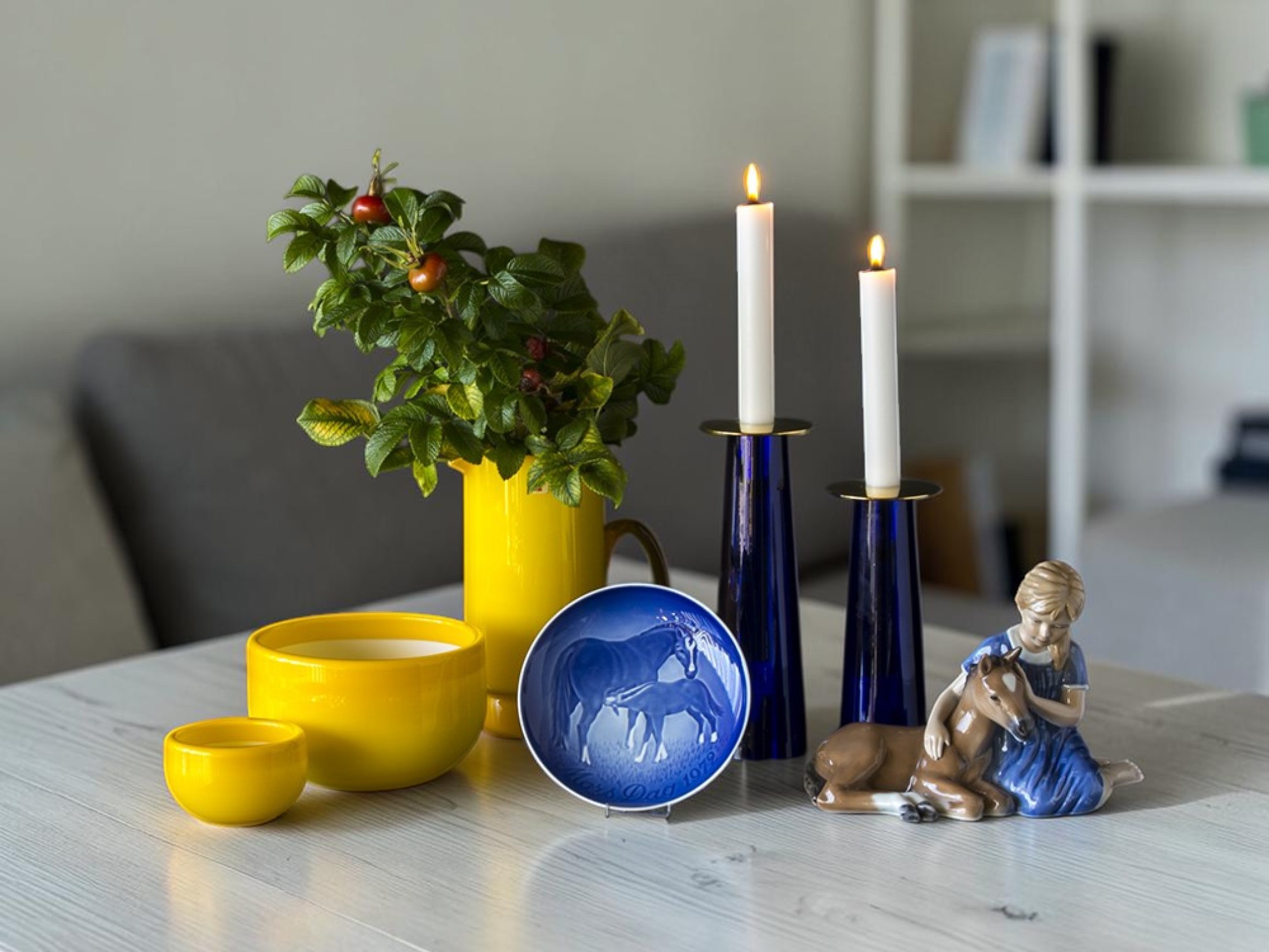 Bing & Grøndahl morsdagsplatte med hest brugt i blå-gul borddekoration med lysestager, skål og Royal Copenhagen figur.