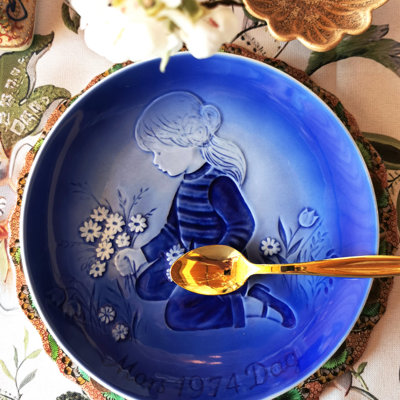 Désirée Mors Dag platte fra 1974 med motiv af pige og blomster, dækket op til sommerdessert med gyldent dessertbestik.