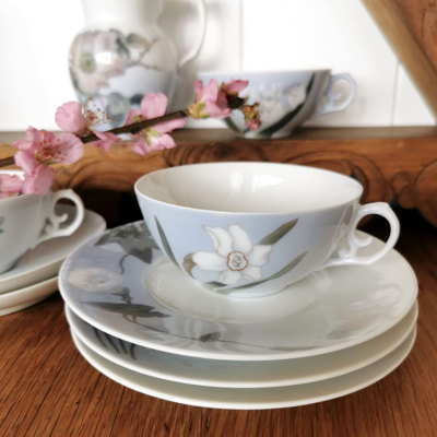 Royal Copenhagen Art Nouveau teservice med håndmalede blomster, dækket op med tekop, underkop og tallerkener i lyseblå og hvide nuancer.