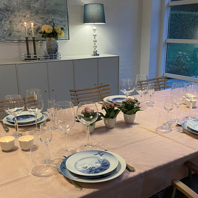 Bord dækket med lyserød dug, Bing & Grøndahl Julerose stel og gamle kaffekopper brugt som blomsterkrukker. Personlig og charmerende borddækning til fest eller hyggelig middag.