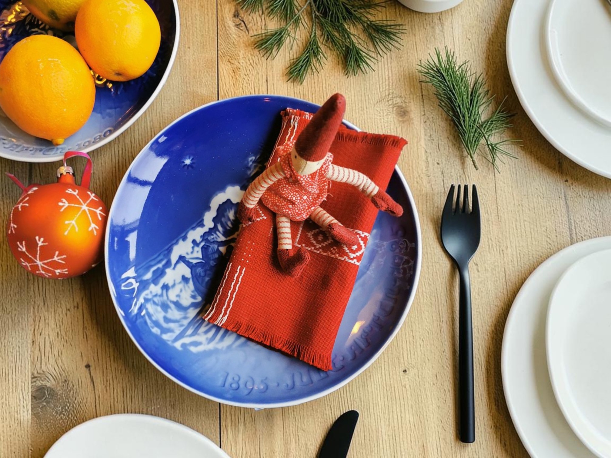 Bing & Grøndahl julejubilæumsplatte dækket op med rød serviet og nisse på julebord med gran og julepynt