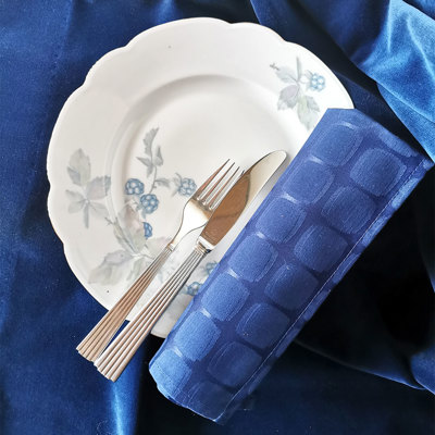 Altrohlau porcelænstallerken med brombærdekoration, dækket med bestik og blå serviet på blå dug. Klassisk og enkel borddækning.