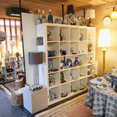 Udstilling med figurer, platter, vaser og porcelæn i blå og hvide nuancer hos DPH Tradings butik i Odense