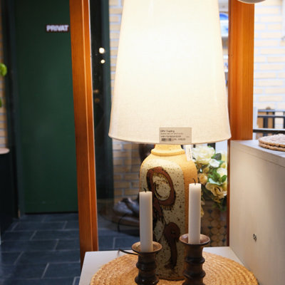 Keramikbordlampe med lys stofskærm og to keramiklysestager – udstillet på en af hylderne hos DPH Tradings butik i Odense
