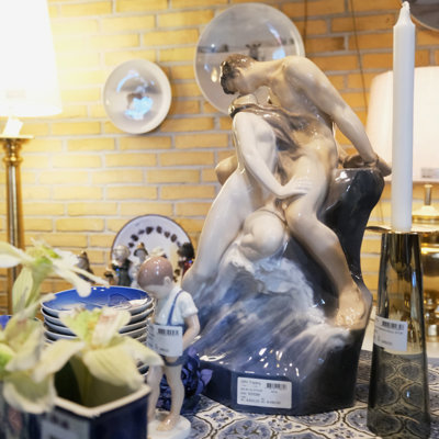 Royal Copenhagen figuren 'Bølge og Strand' af Theodor Lundberg udstillet blandt porcelæn, lysestager og platter i DPH Tradings butik i Odense