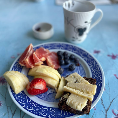 Rörstrand Mors Dag platte brugt som tallerken til morgenbord med frugt, rugbrød med ost og kaffe. Et eksempel på, hvordan blå platter kan bruges til hverdag.