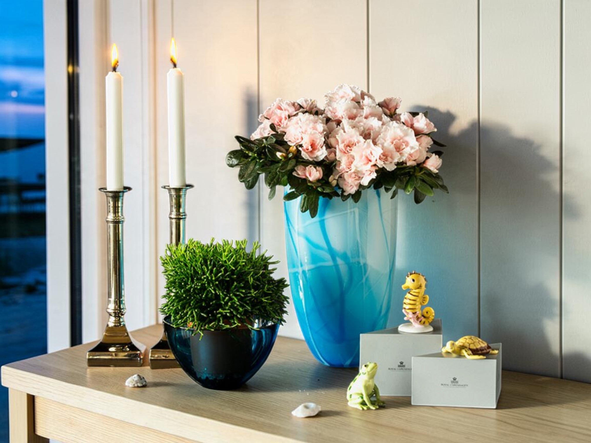 Farverige Fortuna dyrefigurer fra Royal Copenhagen med søhest, frø og skildpadde blandt blomster og lysestager.