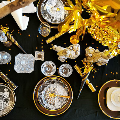 Nytårsbord dækket i sort, hvid og guld med Rörstrand platter fra serien De 10 bud og Orrefors årsplatter i glas. Smukke drikkeglas, festlig pynt og guld detaljer fuldender opdækningen.